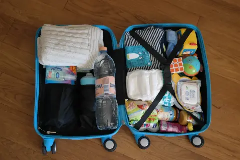 Walizka z rzeczami dla dziecka na podróż samolotem Ryanair: ubranka, pieluchy, zabawki, chusteczki, żel antybakteryjny i jedzenie dla dziecka.