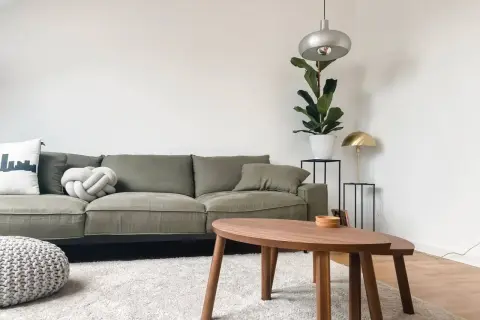 Grüne Couch, die durchgesessen ist, aber mit neuen Kissen und einem Pouf wirkt sie frisch. Ideen für couch durchgesessen aufpolstern selber machen.