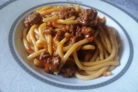 Pici fatti in casa conditi con un ricco ragù di carne, un classico della cucina toscana.