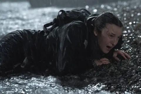 Ellie, wyczerpana i przemoczona, czołga się po kamieniach. To trudne zakończenie The Last of Us 2.