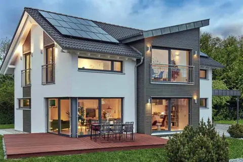 Modernes Haus mit Solaranlage auf dem Dach und großzügigen Fenstern im **Erdgeschoss**, die Einblicke in gemütliche Wohnbereiche gewähren.