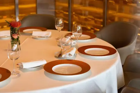 Une table dressée avec élégance, prête pour un repas. Chaque couvert est un pictogramme mettre la table, avec assiettes, verres et serviettes.