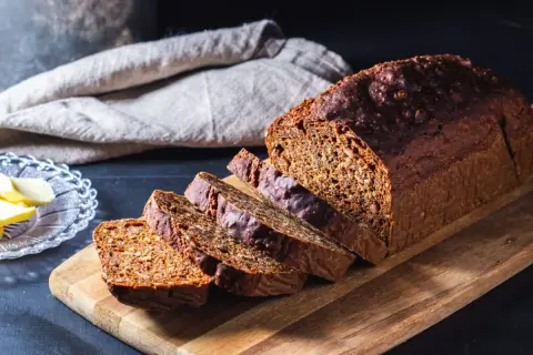 Ett mörkt, saftigt filbröd skuret i skivor, redo att avnjutas med smör.