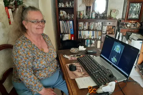 Une femme consulte des archives en Sarthe sur son ordinateur, où s'affiche le portrait d'une religieuse.