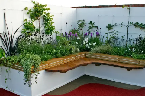 Moderne hochbeet ideen mit integrierter Holzbank und üppiger Bepflanzung in Weiß und Lila.
