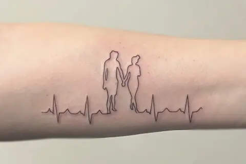 Ein Fineline Tattoo zeigt ein Paar, das Händchen hält, über einer EKG-Linie. Ein schönes Vorher-Nachher-Beispiel für zarte Linienkunst.