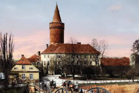Opole stare miasto: zamek z wieżą, mosty, dorożki i kamienne domy pod różowym niebem.