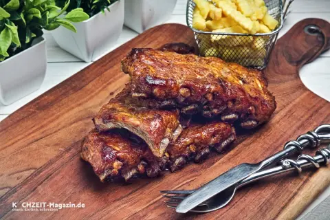 Saftige, geschmorte Rippchen mit knusprigen Pommes Frites auf einem Holzbrett, bereit zum Genießen.