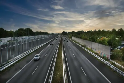 Szeroka autostrada A2 z ruchem samochodowym, otoczona zielenią i ekranami akustycznymi.