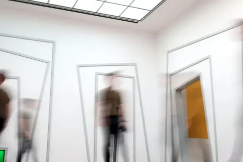 Mensen bewegen door een gang met geometrische openingen, wat een indruk geeft van een sensorische informatieverwerking test.