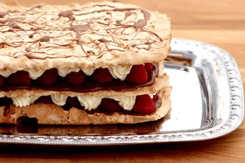 En härlig rice krispies tårta med lager av maräng, grädde, choklad och hallon, dekorerad med chokladsås.