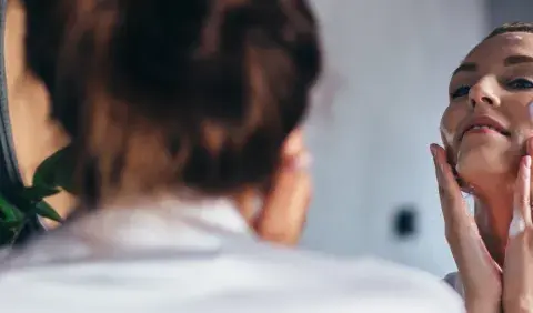 Frau trägt Schaum auf ihr Gesicht auf. Sie fragt sich: "Allantoin, was ist das?" Es ist ein beruhigender Inhaltsstoff für die Haut.