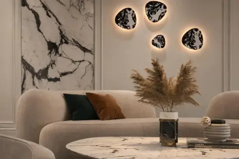 Nowoczesny salon z beżową sofą i marmurowym stolikiem. Na ścianie wiszą dekoracyjne kinkiety z kloszem, tworząc ciepłą atmosferę.