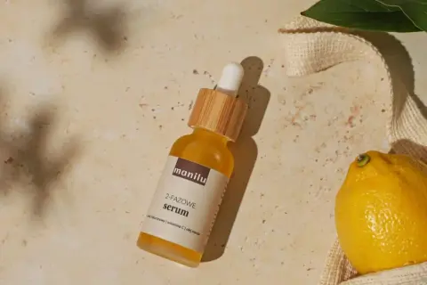 Szukasz idealne serum do twarzy po 50.? Na zdjęciu dwufazowe serum z kwasem hialuronowym, witaminą C i olejem marula, obok cytryny i liści.