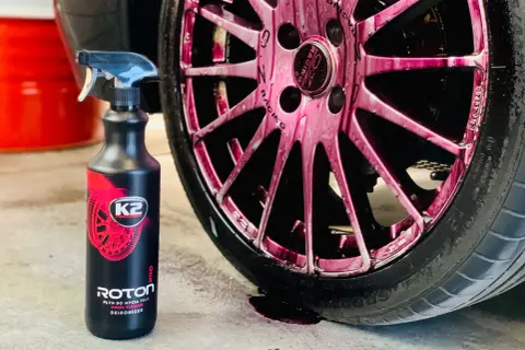 Płyn K2 Roton w sprayu, idealny do czyszczenia felg aluminiowych. Widoczny na różowych felgach, skutecznie usuwa zabrudzenia.