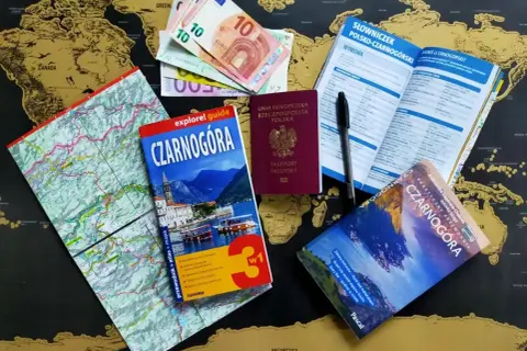 Paszport, pieniądze i przewodniki po Czarnogórze leżą na mapie świata. Czy do Czarnogóry potrzebny jest paszport? Tak, ten polski paszport jest gotowy do podróży!