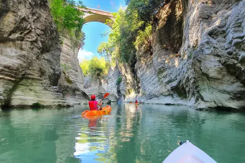 Kayak tra imponenti pareti rocciose, simili a **marmitte dei giganti**, sotto un antico ponte.
