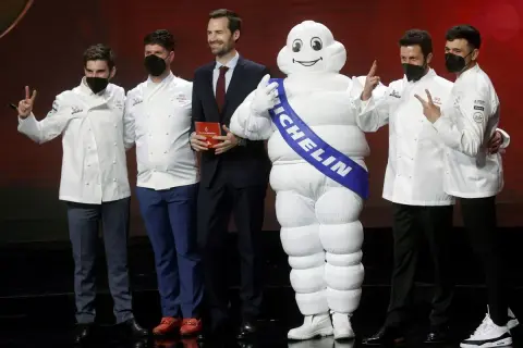 Chefs celebran con el muñeco Michelin, un símbolo de excelencia culinaria y 5 estrellas Michelin.