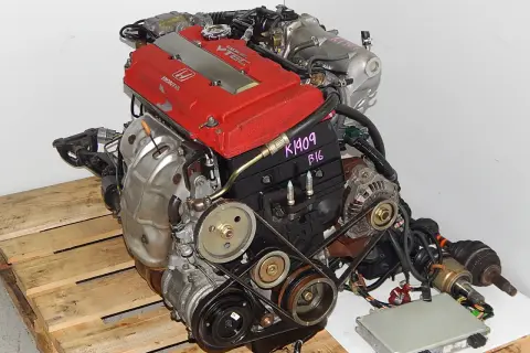 Silnik Honda VTEC z czerwonymi pokrywami zaworów, na drewnianej palecie.