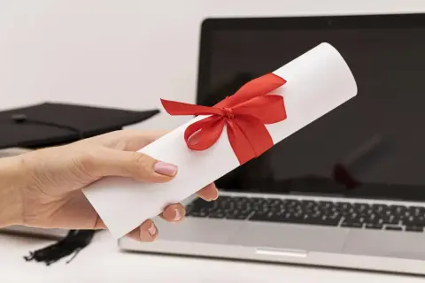 Dyplom z czerwona wstążką, czapka absolwenta i laptop. To zaproszenie dla delegacji z pracy tekst.