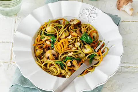 Leckere Spaghetti-Rezepte mit Pilzen, Karottenstreifen und Spinat, garniert mit Nüssen.