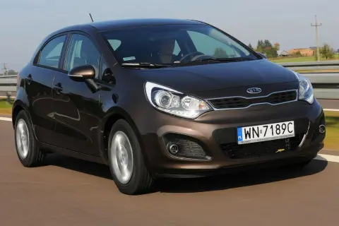 Brązowe Kia Rio 3 w ruchu drogowym, z widocznym kierowcą i tablicą rejestracyjną WN-7189C.