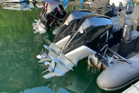 Motori fuoribordo Mercury Verado, con eliche lucide che riflettono l'acqua verde. L'alto bordo del gommone è visibile, pronto per la navigazione.