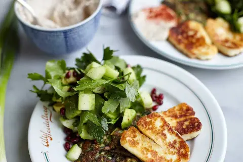 En härlig tallrik med stekt halloumi, en fräsch sallad med gurka och granatäpple, samt en grön röra. Ett perfekt halloumi recept för en lätt måltid.
