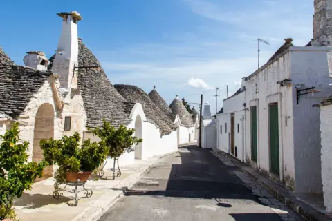 Un vicolo tra i trulli, con i loro tetti conici in pietra, mostra cosa sono i trulli, un'architettura unica della Puglia.