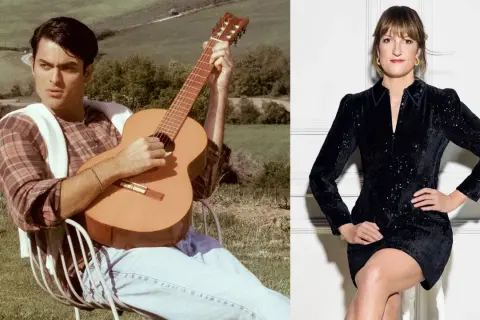 Mężczyzna gra na gitarze w plenerze, kobieta w czarnej sukience siedzi.