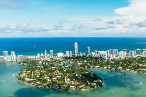 Piękna miami pogoda, błękitne niebo i turkusowa woda otaczają wyspy z luksusowymi willami i drapaczami chmur.