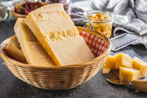 Kawałki sera Grana Padano w koszyku, obok pokrojone w kostkę. To jest właśnie to, co to jest Grana Padano.