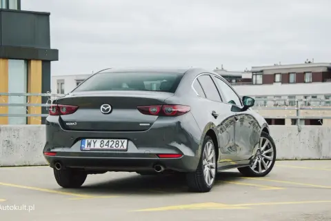 Szary sedan Mazda 3 na parkingu. Sprawdzamy mazda 3 spalanie i wrażenia z jazdy.