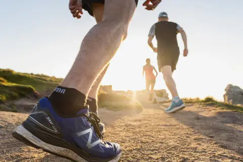 Coureurs sur un sentier de trail en Bretagne, profitant du soleil couchant sur la côte.