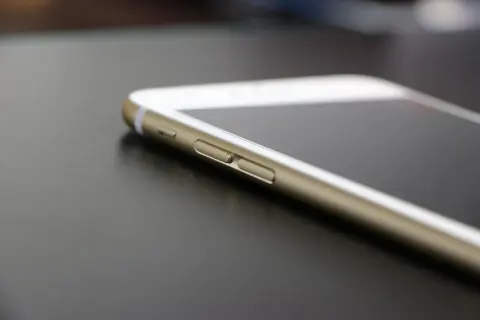 Złoty iPhone leży na ciemnym blacie. Wiesz, jak znaleźć iPhone, gdy go zgubisz?