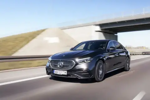 Elegancki, czarny Mercedes E220d pędzi autostradą pod mostem.