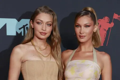 Alana Hadid y su hermana Bella posan juntas en la alfombra roja, luciendo atuendos elegantes y maquillaje impecable.