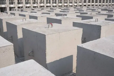 Rząd betonowych bloków, każdy kubik betonu z metalowymi uchwytami, tworzy imponującą strukturę.