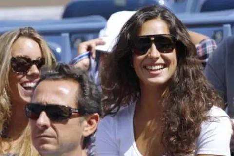 Xisca Perelló, con gafas de sol y una sonrisa radiante, disfruta de un evento deportivo junto a amigos.