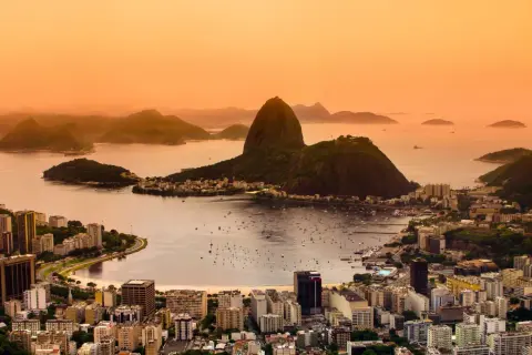 Widok na Rio de Janeiro o zachodzie słońca. W tle góry i zatoka z łodziami. Marzenie o podróży do Brazylii i szczepienia na wyjazd.