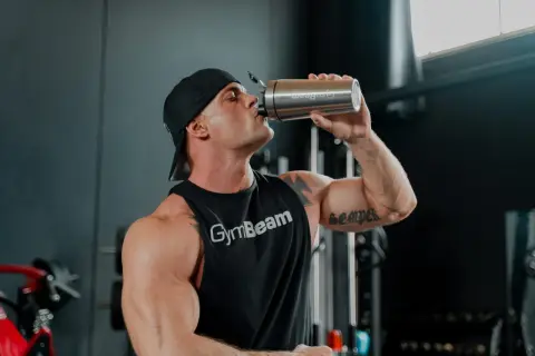 Uomo con muscoli scolpiti beve da un shaker, pronto per la sua integrazione con berberina per massimizzare i risultati.
