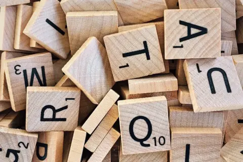 Un tas de tuiles de jeu de mots en bois, avec des lettres comme R, T, A, N, Q. Un jeu de mots amusant, comme en .lower python.