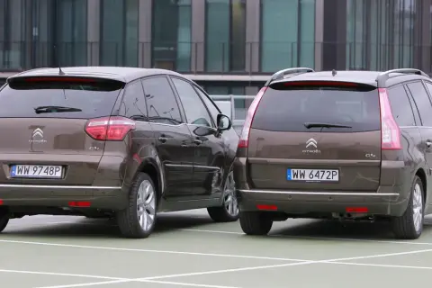 Dwa brązowe Citroen Picasso stoją obok siebie na parkingu.
