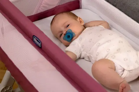Un neonato con ciuccio dorme sereno nella sua culla, un luogo sicuro dove far dormire un neonato.