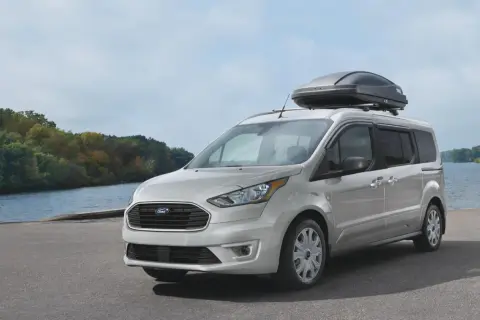 Silver Ford Transit Connect med takbox vid en sjö. Inga problem här, bara en redo för äventyr.
