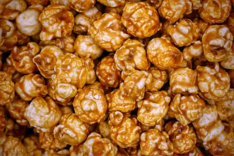 Gros plan sur une montagne de pop-corn caramel, chaque grain enrobé d'une sauce dorée et brillante. Un délice croustillant et sucré.