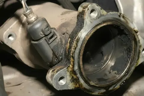 Verrußtes AGR-Ventil mit Kabelstecker. Rußablagerungen deuten auf AGR-Ventil defekt Symptome hin.