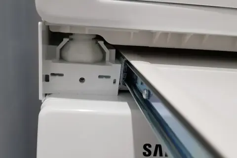 Zbliżenie na mechanizm łącznika suszarki na pralce Samsung, widoczny metalowy wspornik i biała podstawa.