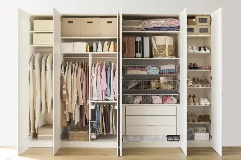 Armario organizado con ropa colgada y doblada, cestas y cajas, siguiendo el método Marie Kondo para un espacio ordenado y funcional.