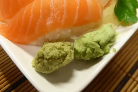 Närbild på sushi med lax och ris, serverad med två klickar grön wasabi. Perfekt för ditt wasabi recept!